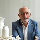 Porträtfoto von Dr. Klaus Richter, umgeben von Porzellanentwürfen.